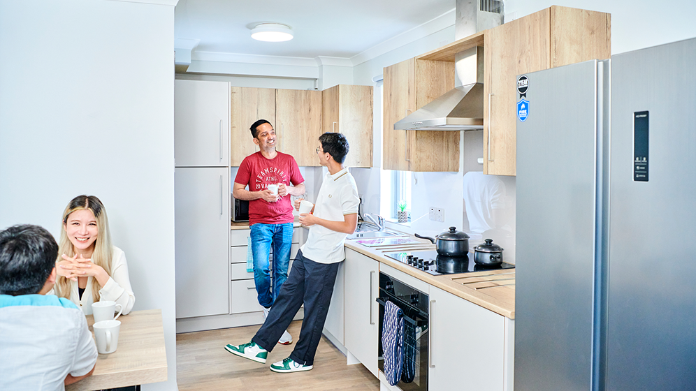 An alternative view of an open plan kitchen showing the breakfast bar. There are two windows and large, flat screen TV on the wall. 